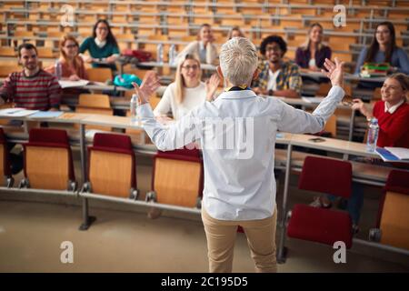 Femme professeur âgé répondant aux questions des étudiants en amphithéâtre Banque D'Images