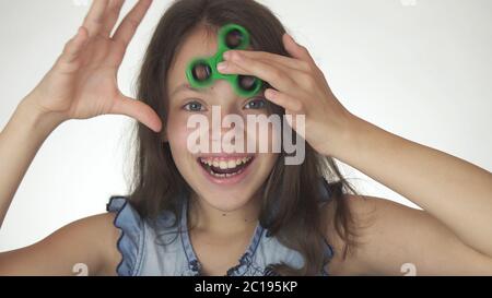 Belle fille joyeuse jouant avec le spinner de figet vert sur fond blanc Banque D'Images