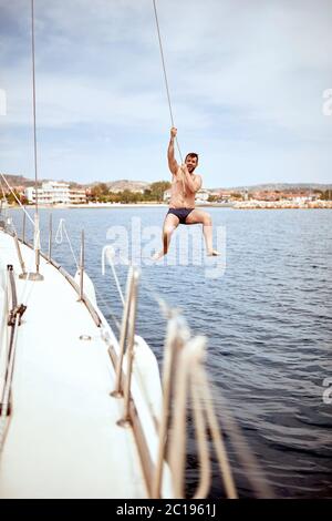 Jeune homme sortir, s'amuser et profiter de journées d'sauter de bateau à voile en mer. Banque D'Images