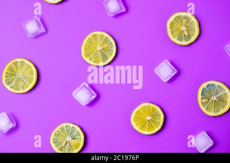 Disposition de la limonade avec des tranches de citron juteux, des glaçons sur fond violet Banque D'Images