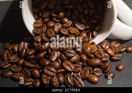 Des grains de café débordent de la tasse Banque D'Images