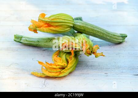Jeunes courgettes ou courgettes avec des fleurs d'orange comestibles fixées sur une table sur un marché agricole avec un espace copie ci-dessous Banque D'Images
