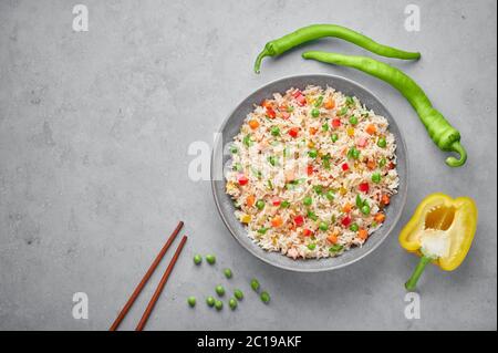 Légumes de riz frit dans un bol gris sur une table en béton. Le riz frit est un plat de cuisine chinoise indo. Repas végétarien indien. Cuisine asiatique. Copier l'espace. Haut vi Banque D'Images