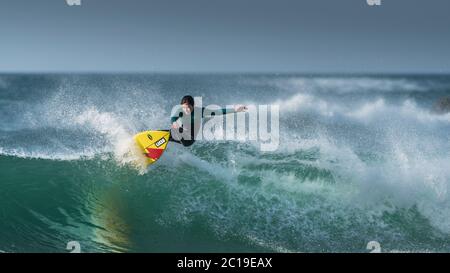 Une image panoramique d'un jeune adolescent en action de surf à Fistral à Newquay, en Cornouailles. Banque D'Images