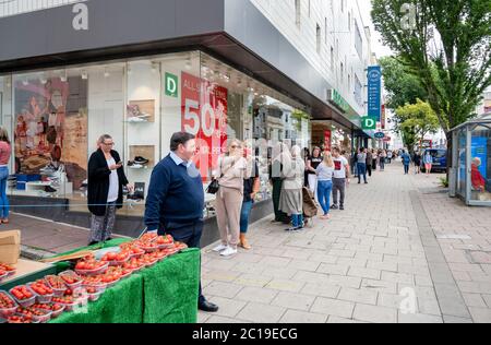 Brighton Royaume-Uni 15 juin 2020 - UN détenteur de fruits et légumes frais ne peut que regarder les files d'attente énormes de clients attendre pour arriver dans le magasin Primark de Western Road Brighton tôt ce matin, car les magasins non essentiels rouvrent en Angleterre aujourd'hui après que les restrictions de confinement ont été assouplies plus tard Crise pandémique du coronavirus COVID-19 : Credit Simon Dack / Alay Live News Banque D'Images