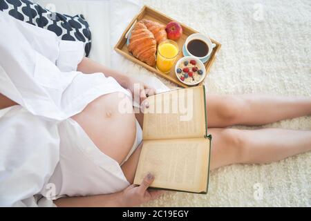 Femme enceinte le petit-déjeuner avec café, jus d'orange, croisan et le gruau. Banque D'Images