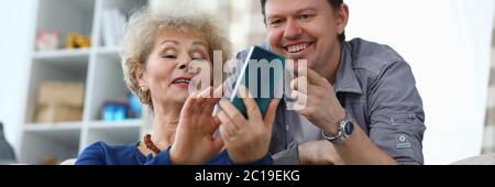 La mère âgée montre une photo au téléphone au fils adulte Banque D'Images