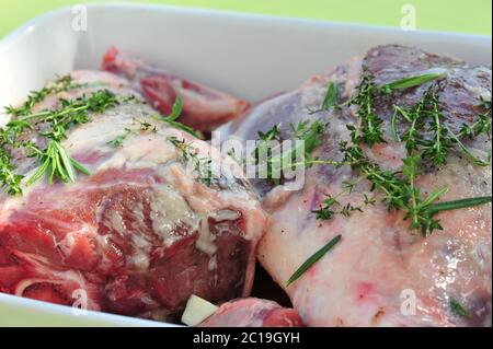 Vue rapprochée de l'agneau frais cru arrosé de thym et prêt à cuire. Banque D'Images