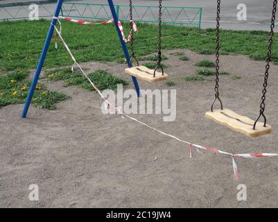 Aire de jeux pour enfants empy et balançoire fermées pour le coronavirus ou le Covid19. Enveloppé dans du ruban de police en raison d'une quarantaine Banque D'Images