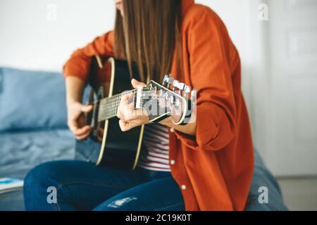 Le guitariste joue de la guitare. Ou une fille apprend à jouer la guitare à la maison. Frais de scolarité individuels à domicile. Banque D'Images