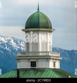 Bâtiment carré extérieur avec dôme vert et toit contre la neige de montagne et ciel nuageux Banque D'Images