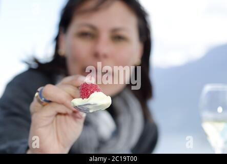 Cuillère Holdinga femme avec framboise et crème glacée. Banque D'Images