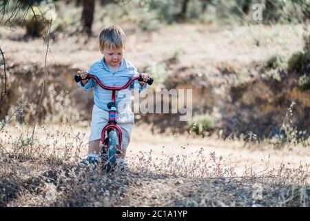 Mignon blond tout-petit à vélo dans la forêt Banque D'Images