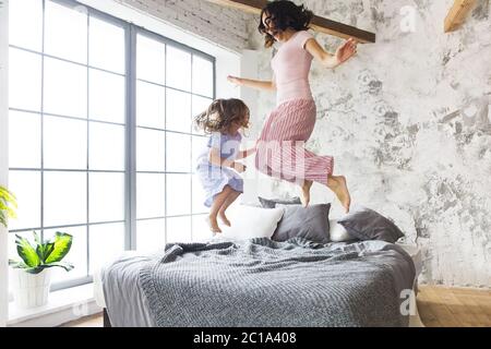 Plaisir en famille. Mère et fille sautant sur le lit Banque D'Images