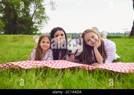 Famille heureuse avec un chien husky couché sur l'herbe dans le parc d'été. Banque D'Images