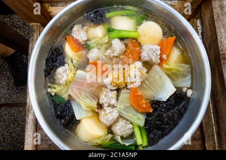 Soupe claire avec tofu, porc haché et divers légumes dans une casserole métallique. Banque D'Images