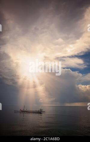 Petit bateau de pêcheur sur la mer calme au coucher du soleil Banque D'Images