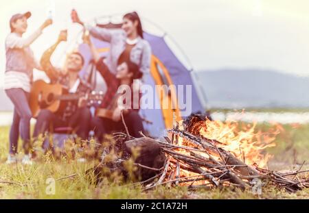 Groupe d'amis s'amusant ensemble et de boire au camping près du lac et de mountien dos. Banque D'Images