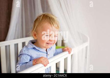 Portrait de bébé s'ennuie dans l'article de bébé. Bébé garçon seul dans un lit bébé. Triste petit bébé. Lonely baby in bed Banque D'Images