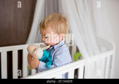 Portrait de bébé s'ennuie dans l'article de bébé. Bébé garçon seul dans un lit bébé. Triste petit bébé. Lonely baby in bed Banque D'Images