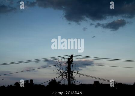 poteau électrique de désordre avec fils fond nuages sombres avec sillhoutte Banque D'Images
