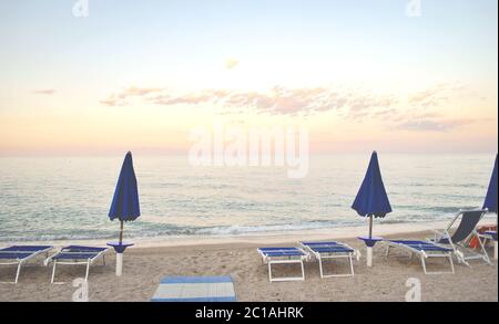 deux parasols fermés et quelques chaises longues sur une plage déserte Banque D'Images