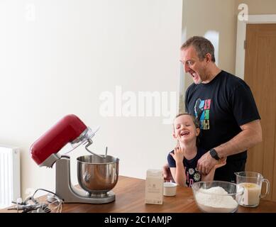 Papa et fille font de la pâte à pizza fraîche dans le batteur de cuisine. Corona Lockdown cuisine. Préparation de pizza avec Daddy pendant le verrouillage. Banque D'Images