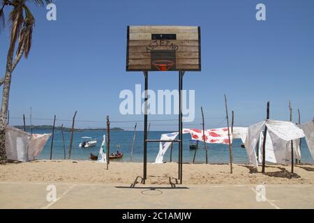 Nappes à vendre suspendues à la vente devant le terrain de basket-ball sur la plage avec des bateaux, village d'Ampangorinana, île de Nosy Komba, Madagascar. Banque D'Images