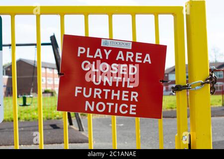 Aire de jeux fermée pendant le verrouillage du coronavirus. Panneau rouge Metropolitan Borough Council avec porte jaune vif et balançoire pour enfants vide en arrière-plan. Banque D'Images