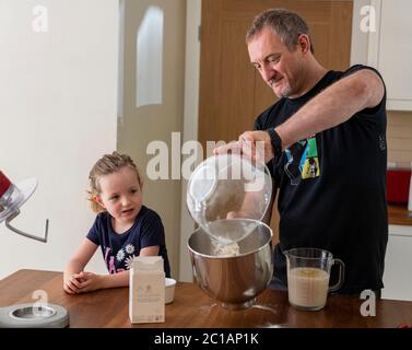 Papa et fille font de la pâte à pizza fraîche dans le batteur de cuisine. Corona Lockdown cuisine. Préparation de pizza avec Daddy pendant le verrouillage. Banque D'Images