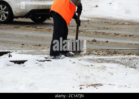 l'ouvrier nettoie les voies ferrées de la neige avec une pelle à la place du passage à niveau de la voie ferrée automobile Banque D'Images