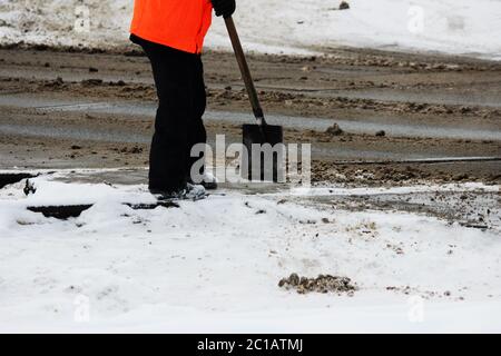 l'ouvrier nettoie les voies ferrées de la neige avec une pelle à la place du passage à niveau de la voie ferrée automobile Banque D'Images