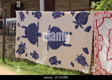 Nappes à vendre suspendues à la vente sur trottoir, Village d'Ampangorinana, île de Nosy Komba, Madagascar. Banque D'Images