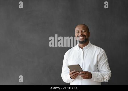 Homme d'affaires afro-américain souriant utilisant une tablette par un tableau noir Banque D'Images