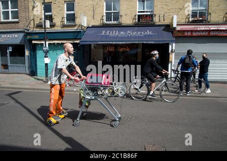 Hackney, Londres, juin 2020 pendant la pandémie de Covid-19 (coronavirus). Marché de Broadway. Fermé à la circulation. Un homme sur un segway pousse un chariot de shopping W Banque D'Images