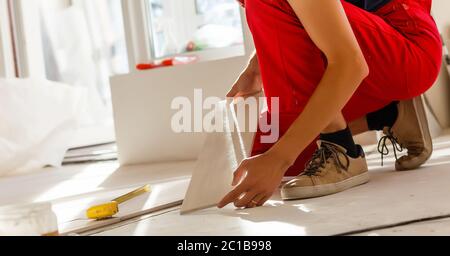 Les mains des travailleurs de placer des entretoises entre carreaux de sol en céramique - close up Banque D'Images