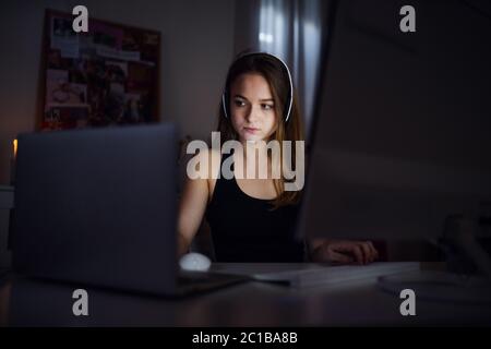 Jeune fille ennuyé avec ordinateur assis à l'intérieur, concept de chat en ligne. Banque D'Images