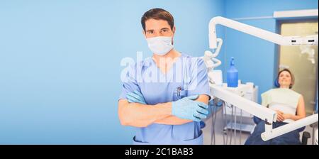 Jeune souriant beau médecin masculin en uniforme médical, masque médical jetable avec équipement dans le bureau de la dentisterie et patient heureux dans le Banque D'Images