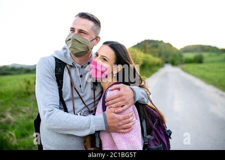 Couple heureux en voyage à l'extérieur dans la nature, portant des masques faciaux. Banque D'Images