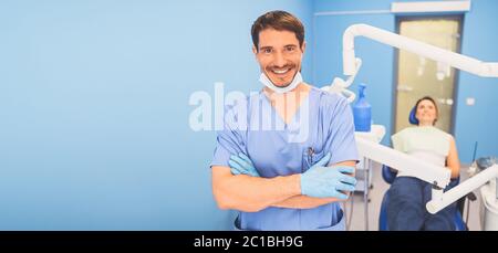 Jeune souriant beau médecin masculin en uniforme médical, masque médical jetable avec équipement dans le bureau de la dentisterie et patient heureux dans le Banque D'Images