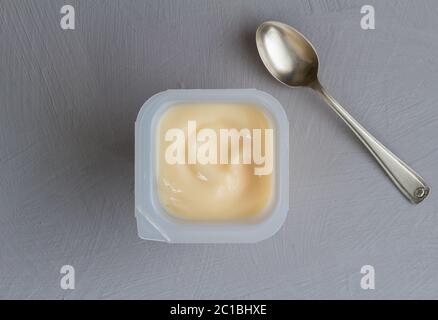 Yogourt sain aux fruits de pêche avec coloration naturelle dans une tasse en plastique isolée sur texture grise b Banque D'Images