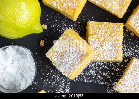 Barres de citron en gros plan sur fond noir - vue du dessus photo de petits carrés de citron cuits avec le haut de la page Banque D'Images