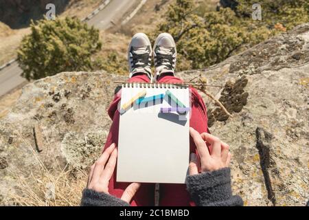 Vue de la première personne sur les genoux de la femme est un carnet avec craies pour dessiner des pastels. Mains de femmes tenant un ordinateur portable dans n Banque D'Images