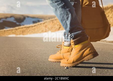 Marcher sur le coucher du soleil d'été sur l'asphalte, les jambes des hommes en chaussures jaunes et les jeans bleus vont le long de l'asphalte. À côté de la vintage Banque D'Images