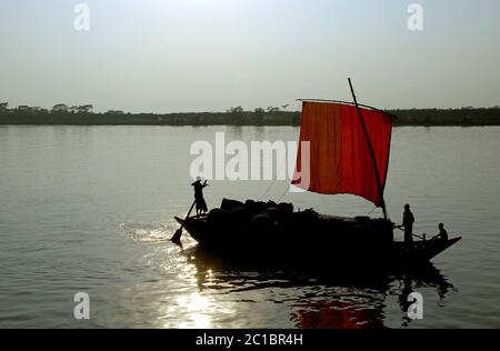 Silhouette d'un bateau à voile orange sur la rivière Rupsa (Rupsha) près de Mongla au Bangladesh. Personnes non identifiables. Banque D'Images