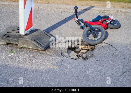 Equilibrer le vélo (pousser le vélo) à côté de la pothole sur la rue asphaltée avec le panneau de signalisation routière d'alerte de détour Banque D'Images