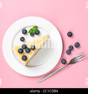 Cheesecake avec bleuets sur plaque isolée sur fond blanc, vue du dessus Banque D'Images