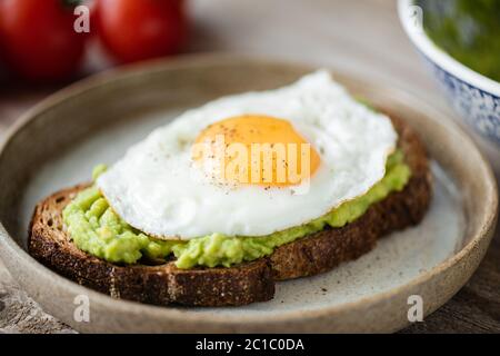 Toast avec avocat et œuf ensoleillé sur l'assiette. Vue en gros plan. Petit déjeuner ou déjeuner savoureux Banque D'Images