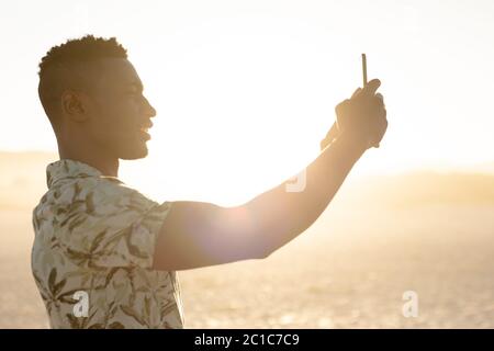 Homme amérindien africain prenant des photos sur la plage Banque D'Images