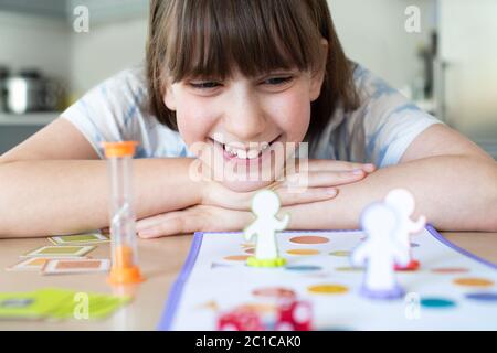 Fille souriante jouant à jeu de société générique à la maison Banque D'Images